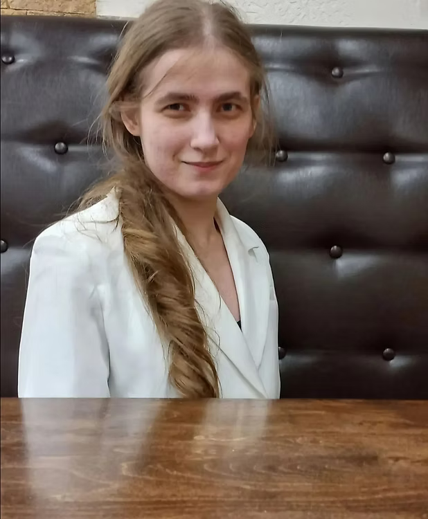 Психолог Анастасия Ильинская сидит за столом в светлом кабинете